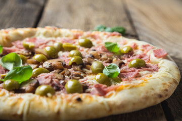 Pizza with prosciutto, olives and fresh basil