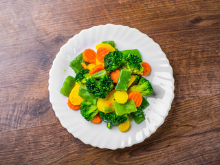 Mixed vegetables. green bean, broccoli and carrots in white plate on a wooden table background. 