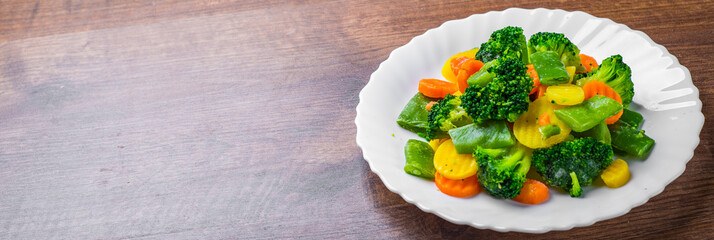Mixed vegetables. green bean, broccoli and carrots in white plate on a wooden table background. 