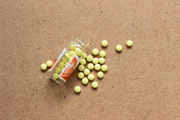 Yellow pills with bottle on green mint background, Healthy and Medicine concept. Yellow tablets. Yellow pills on a brown surface. Yellow tablets on a dark surface