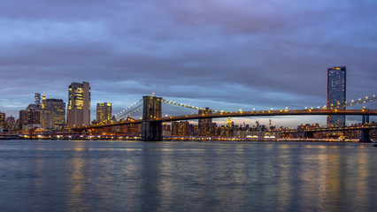 Panorama scene of Brooklyn Bridge beside the east river with New york Cityscape at the twilight time, USA downtown skyline, Architecture and building with tourist concept