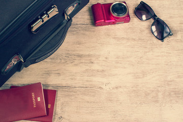 Naklejka premium accessories and items for travel on wooden board. Suitcase, passports, sunglasses, camera. Flat lay, top view. Vacation planning concept.