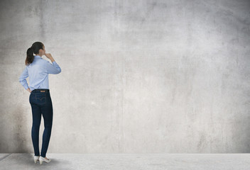 Young woman looking at the wall with space for your text or image. thinking and analysing idea.