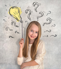 Little girl portrait standing next to the wall with lots of drawn question marks and light bulb. Education concept drawing with icons and symbols. 