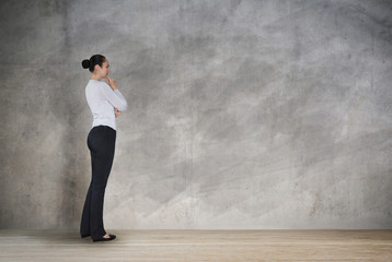 Young woman looking at the wall with space for your text or image. thinking and analysing idea.