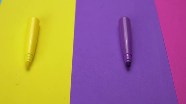Set of a variety of non-permanent markers on colorful paper moves from right to left. Abstract minimal background with space for text. Back to school concept.