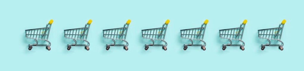 Shopping cart in row on blue background. Minimalism style. Toy trolley for supermarket. Top view or...