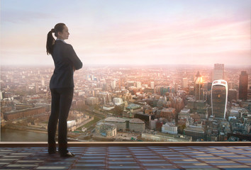 Young woman looking over the City of London business and banking aria with skyscrapers at sunset. Future, new business opportunity, freedom and stability. London, UK - obrazy, fototapety, plakaty