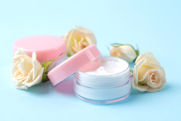 cosmetics for face and body. Cream in pink bottles with fresh roses on a gentle blue background. creams and lotion. spa.