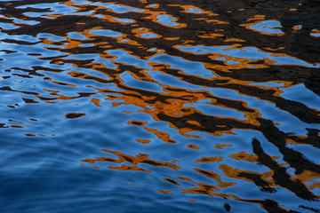 close up of a calm wave with orange water reflection in a soft backlight