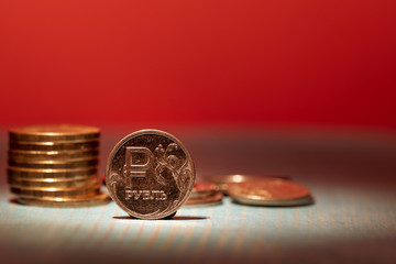 on a red gloomy background metal coin Russian ruble in stacks and the front side, snatched a beam...