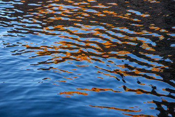 close up of a calm wave with orange colored water reflection in a soft backlight