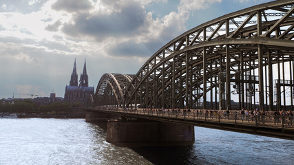 Cologne hohenzollern bridge at midday with many pedestrians, tourists walking on the bridge 