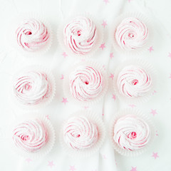 Top view of composed white sweet marshmallows on pink background