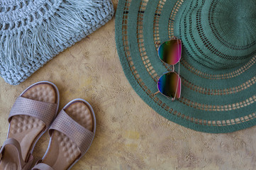Flat lay of summer accessories and shoes on yellow sand background. Summer outfit concept.