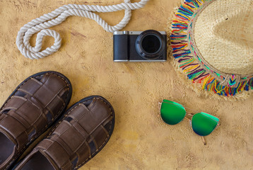 Summer lifestyle concept with hat, smartphone and camera. Summer accessories flat lay on sand background. 