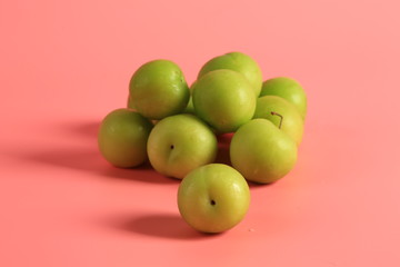 Green cherry plum on a pink background. Creative minimalist style. healthy food