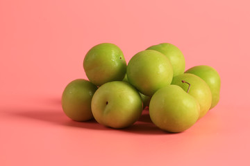 Green cherry plum on a pink background. Creative minimalist style. healthy food