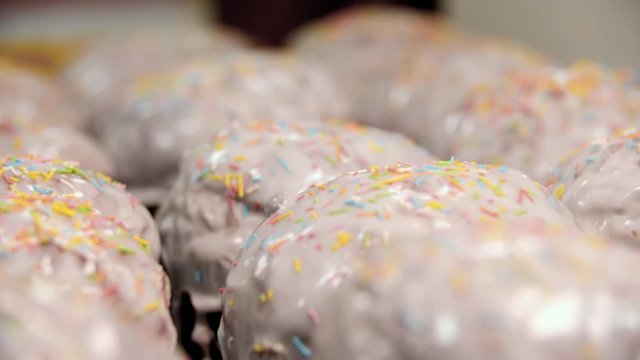 Close-up of glazed easter cakes. Stock footage. Traditional easter cakes covered with white sugar glaze and decorated with rainbow sprinkles
