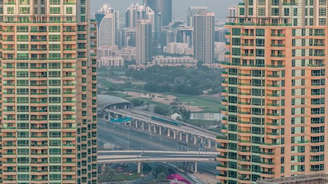 Metro station near Dubai Internet City and Dubai Media City districts as well as Golf Club evening timelapse. Aerial view from Dubai marina with traffic on a highway. Greens and tecom district on