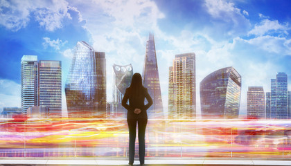 Obraz premium Young woman looking over the City of London business and banking aria with skyscrapers at sunset. Future, new business opportunity, freedom and stability. London, UK