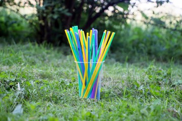 Plastic pollution with plastic straws in the grass