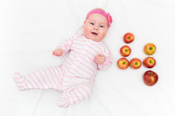 Cute little baby girl laying on white background with fresh red-green apples in shape of number four