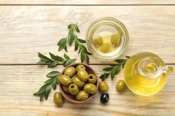 Foto op Plexiglas Green olives in a bowl with leaves and olive oil on a natural wooden table. top view © MK studio