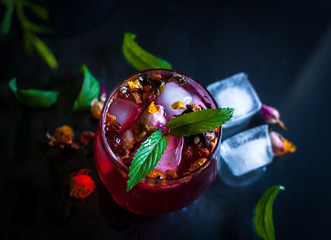 Close-up of homemade flower ice tea in a glass with fresh mint, on dark background