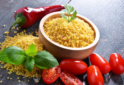 Bowl of uncooked bulgur on wooden table