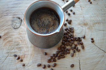 Coffee beans and fresh, aromatic coffee in the Turk on Wooden background