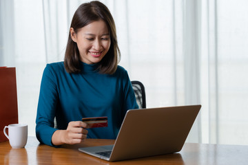 Happy Asian woman shopping online and paying by credit card.technology and ecommerce concept