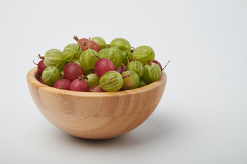 Gooseberries fruits on white background. Bowls with gooseberries isolated on white background. Red and green gooseberries in a bowl with copy space for text. Ripe gooseberry close-up.  K