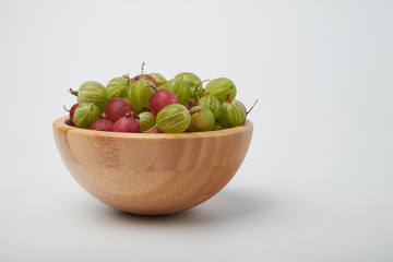 Gooseberries fruits on white background. Bowls with gooseberries isolated on white background. Red and green gooseberries in a bowl with copy space for text. Ripe gooseberry close-up.  K