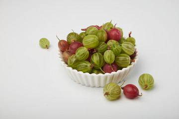 Gooseberries fruits on white background. Bowls with gooseberries isolated on white background. Red and green gooseberries in a bowl with copy space for text. Ripe gooseberry close-up.  K