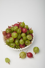 Gooseberries fruits on white background. Bowls with gooseberries isolated on white background. Red and green gooseberries in a bowl with copy space for text. Ripe gooseberry close-up.  K