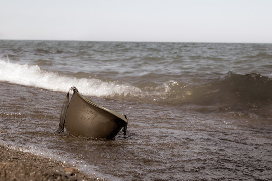 vintage photo of military helmet on beach in the water.  