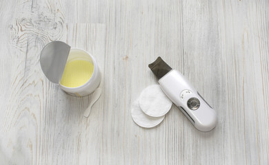 Cosmetic flat lay with ultrasonic scrubber, cotton round disks and patches with vitamin c on grey wooden background.
