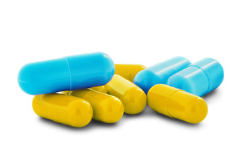 Pile of medical pills in yellow and blue colors on white isolated background with shadow.