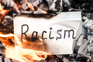 White paper with text of racism burning in fire. The concept of racism. Discrimination, racial problems