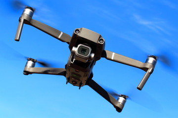 Flight of the drone against the blue sky on a sunny day. View from the front.