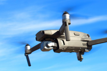 Flight of the drone against the blue sky on a sunny day. View from the side.