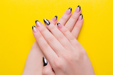 Manicure on female hands close up. Girls hands with a manicure on a yellow background.