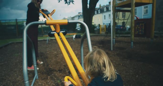 Toddler on seesaw being lifted by his mother