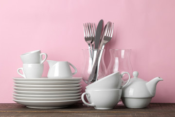 Fototapeta na wymiar Piles of white ceramic tableware, plates, saucers, cups on a pink background. kitchenware.