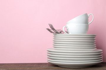 Piles of white ceramic tableware, plates, saucers, cups on a pink background. kitchenware.