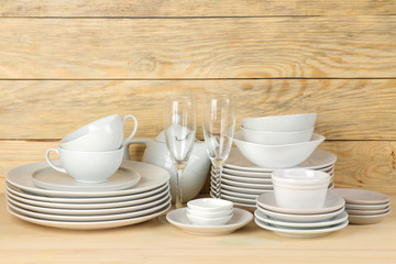 Piles of white ceramic tableware, plates, saucers and cups on a natural wooden background. kitchenware.
