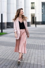 young light-skinned relaxed girl in fashionable clothes walks along the street with a great mood. Lifestyle