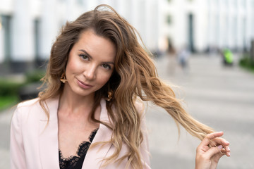 Obraz premium portrait of a girl with long wavy hair, a very beautiful face and an attractive smile. Street close-up in good summer weather. A great option for advertising.