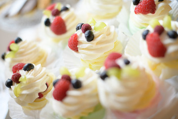 Delicious custard and berries cupcakes,  assortment of sweets and cakes display at a candy buffet. Tasty desert variety catered for a birthday party, wedding reception, a restaurant or a formal event